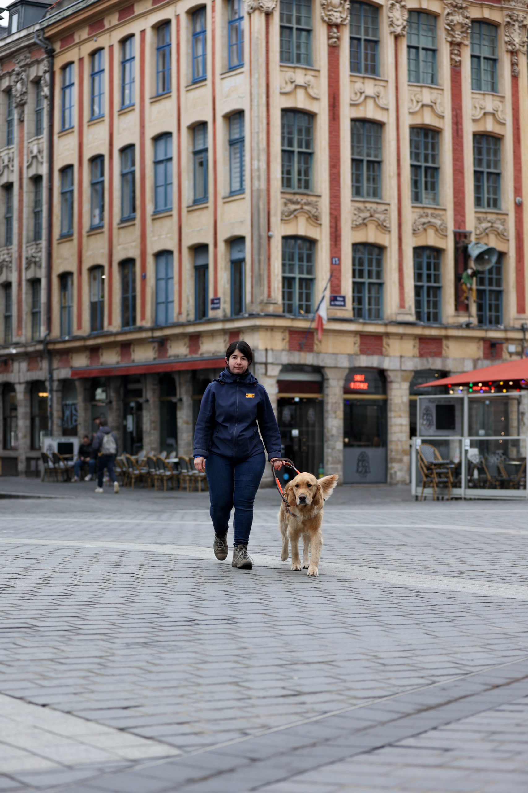 une monitrice marche avec son chien guide, un golden retriever